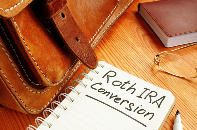 Desk with a notepad labeled “Roth IRA Conversion,” symbolizing retirement tax planning and strategic Roth conversion decisions.