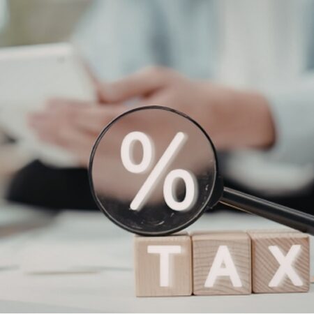 Tax planning concept with magnifying glass highlighting percentage symbol over tax blocks, representing strategies to create tax-free income in retirement