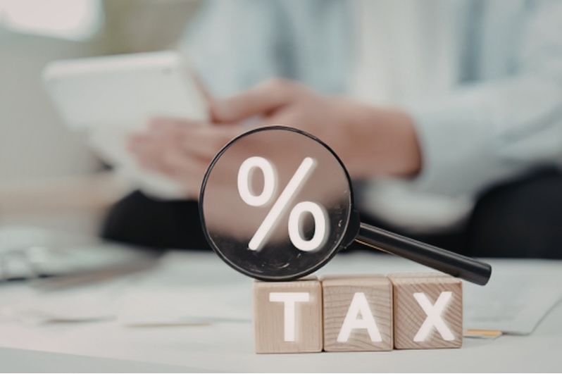 Tax planning concept with magnifying glass highlighting percentage symbol over tax blocks, representing strategies to create tax-free income in retirement
