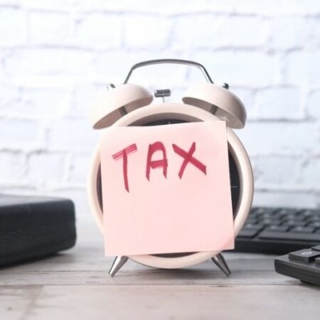Alarm clock with a sticky note labeled “TAX” on it, symbolizing the timing and planning needed to manage taxes on annuity income effectively.