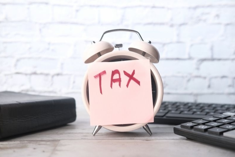 Alarm clock with a sticky note labeled “TAX” on it, symbolizing the timing and planning needed to manage taxes on annuity income effectively.